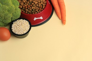 Photo of Dry pet food and products on beige background, space for text