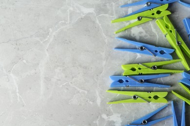 Colorful plastic clothespins on grey table, flat lay. Space for text