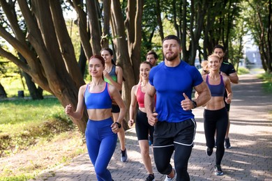 Group of people running in park on sunny day