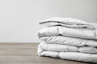 Photo of Soft folded blanket on wooden table, closeup. Space for text