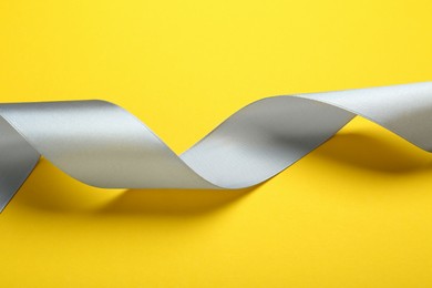 Beautiful ribbon on yellow background, closeup view