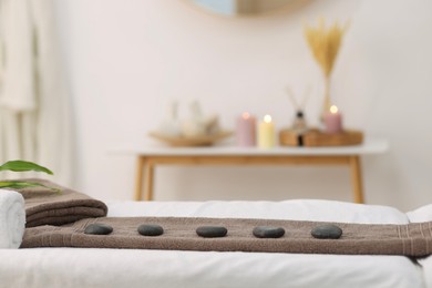 Photo of Towel with arranged spa stones on massage table in recreational center
