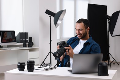 Photo of Young professional photographer with camera in modern photo studio, space for text