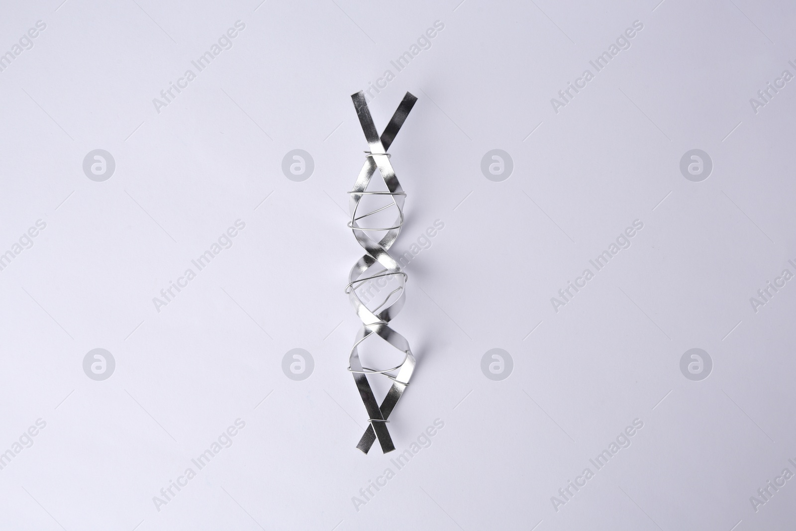 Photo of DNA molecular chain made of metal on white background, top view