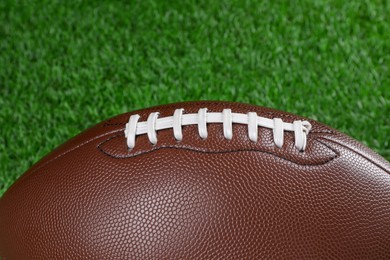 American football ball on green grass, closeup
