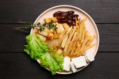 Delicious parsnip with lettuce, feta cheese and dates on black wooden table, top view