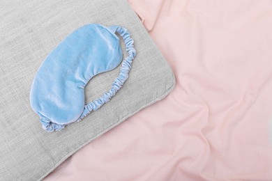 Photo of Light blue sleep mask on beige cloth, top view. Space for text