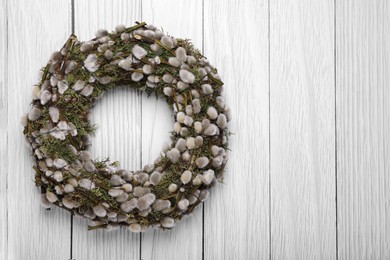 Wreath made of beautiful willow flowers on white wooden table, top view. Space for text