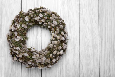 Photo of Wreath made of beautiful willow flowers on white wooden table, top view. Space for text