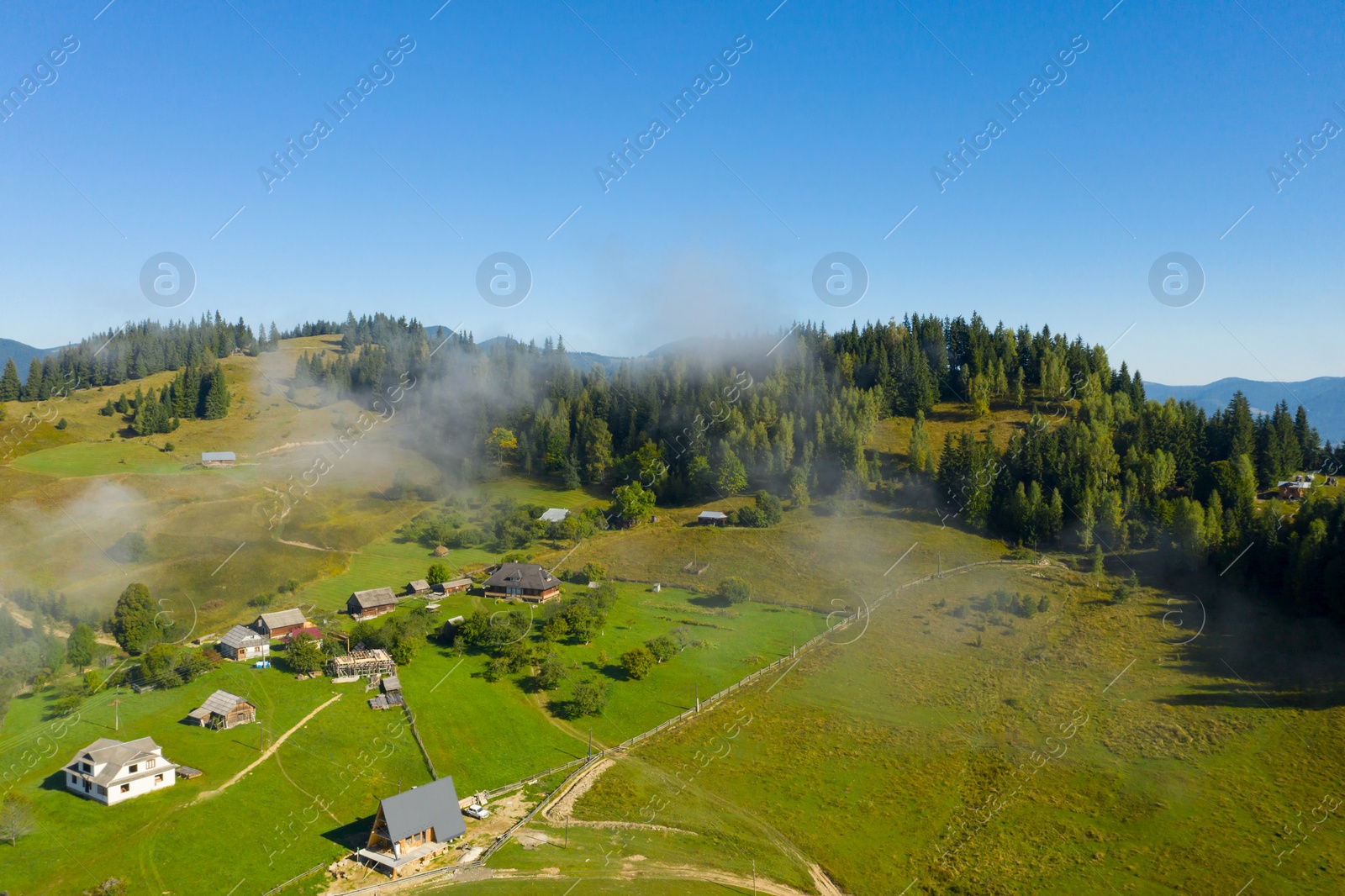 Image of Aerial view of beautiful landscape with misty forest and village in mountains