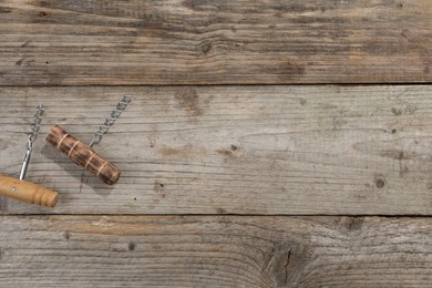 Different corkscrews on wooden table, flat lay. Space for text