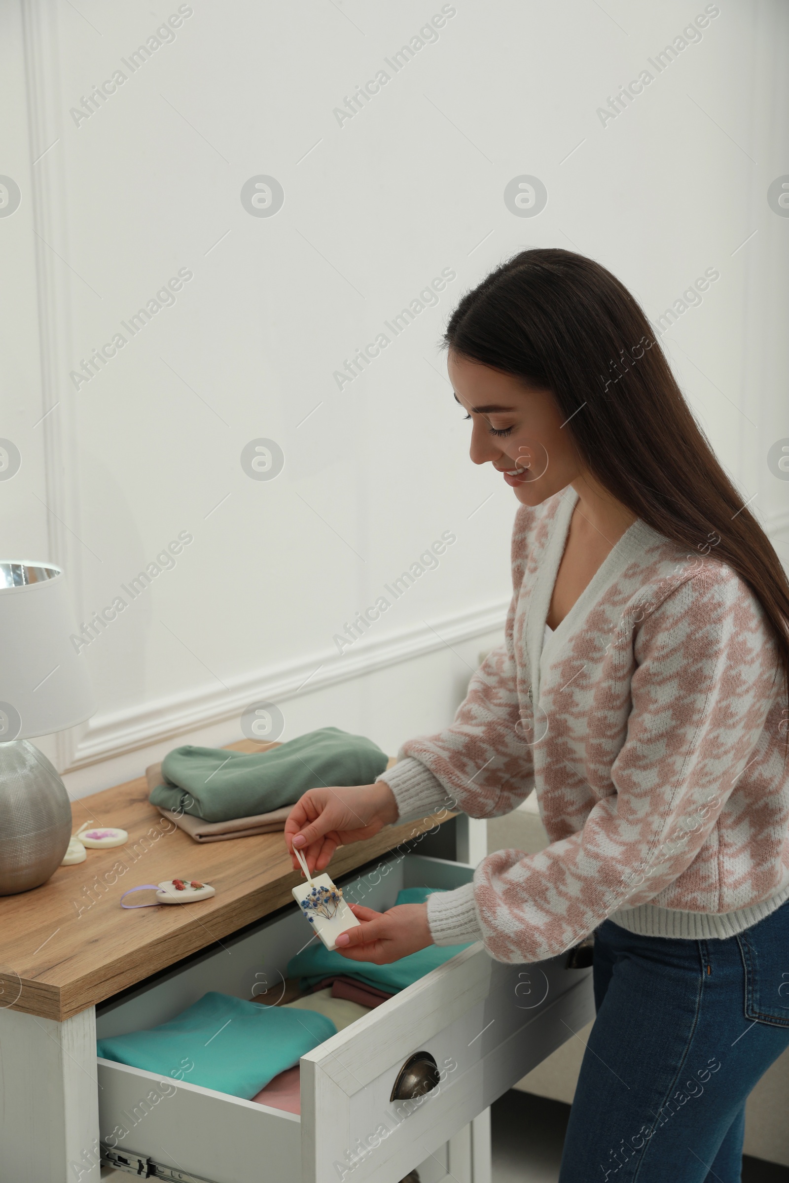 Photo of Woman putting scented sachet into drawer with clothes