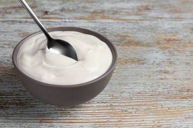 Photo of Ceramic bowl with delicious organic yogurt on wooden table, closeup. Space for text