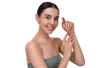 Beautiful young woman holding skincare ampoule on white background