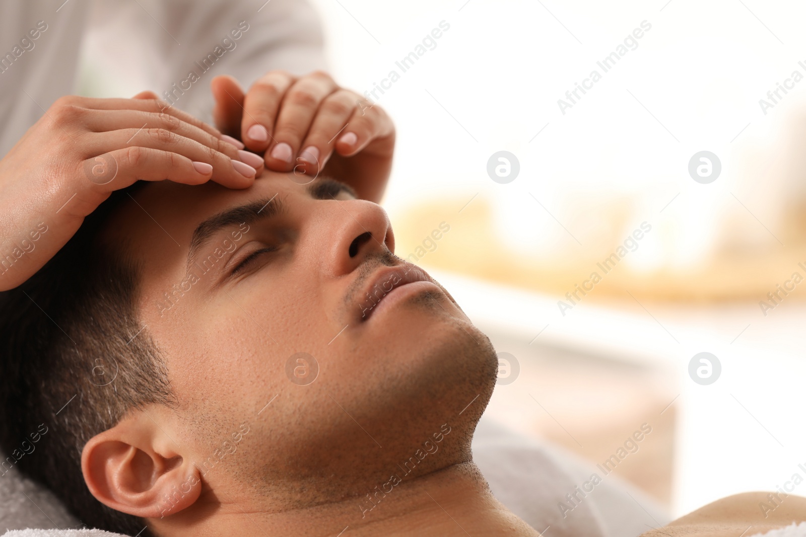 Photo of Man receiving facial massage in beauty salon, closeup