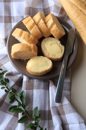 Photo of Whole and cut baguettes with fresh butter on table, above view