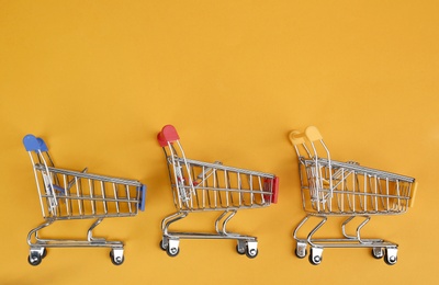 Flat lay composition with empty shopping trolleys on color background. Space for text