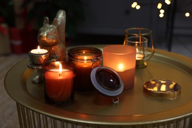 Burning candles in different holders on table indoors