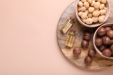 Photo of Delicious organic Macadamia nuts and cosmetic oil on beige background, flat lay. Space for text