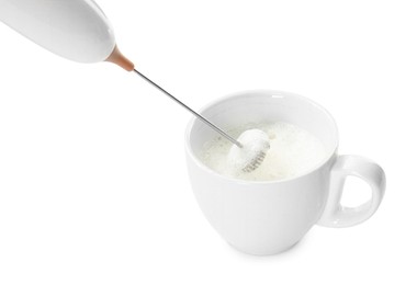 Whisking milk in cup with mini mixer (frother wand) isolated on white, closeup