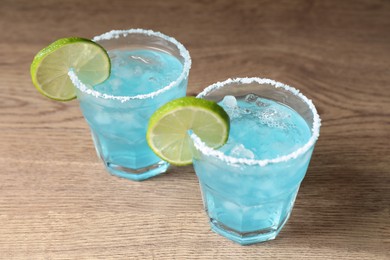 Photo of Refreshing light blue cocktail on wooden table
