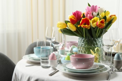 Photo of Easter celebration. Festive table setting with beautiful flowers and painted eggs