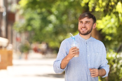 Photo of Young man with cup of delicious milk shake outdoors