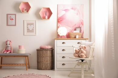 Photo of Stylish child's room interior with beautiful pictures and chest of drawers