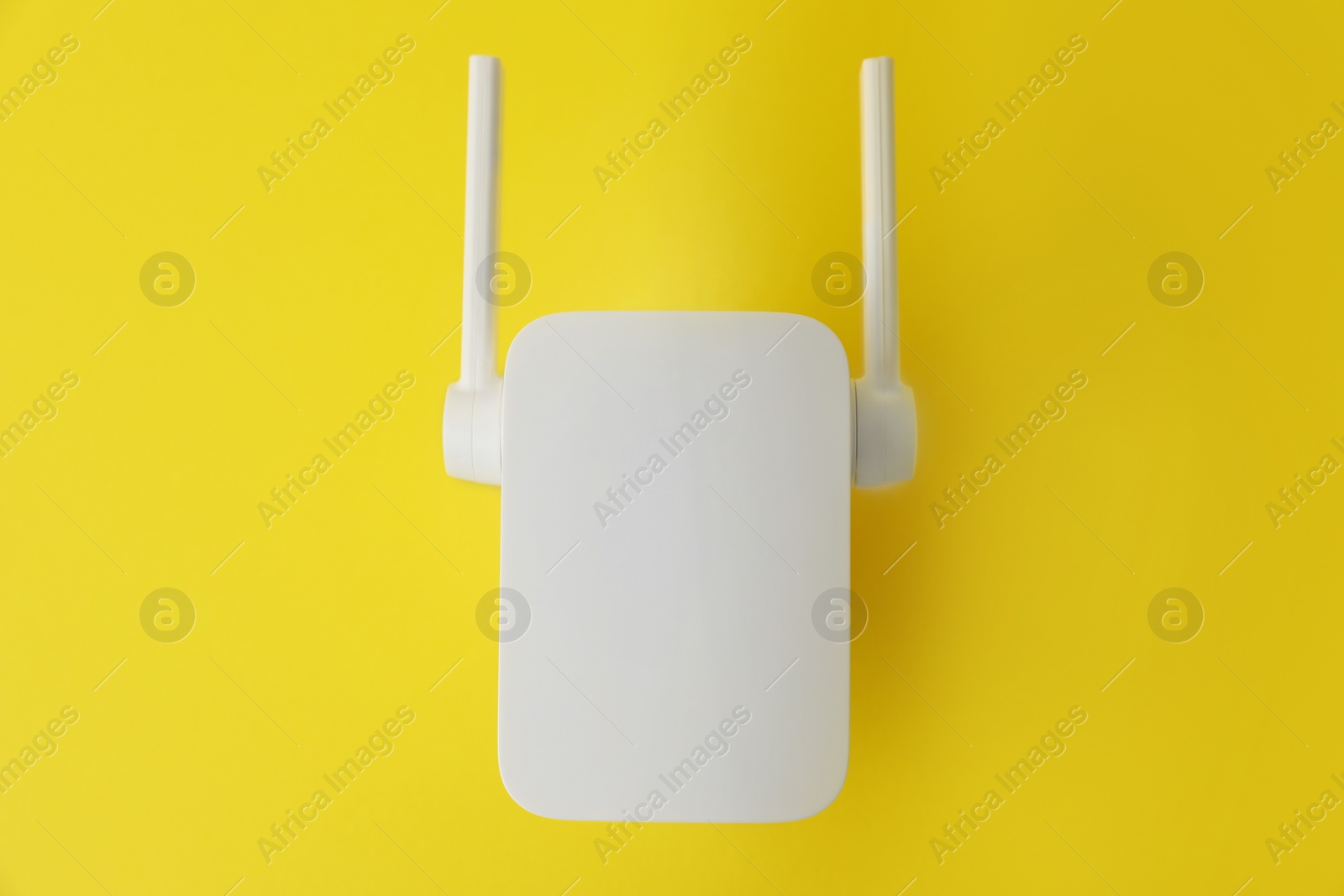 Photo of New modern Wi-Fi repeater on yellow background, top view