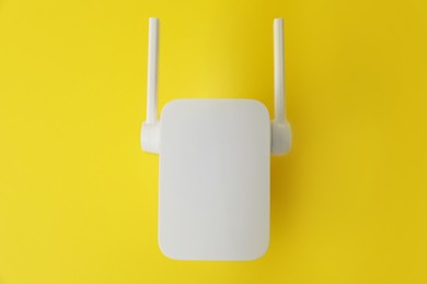 Photo of New modern Wi-Fi repeater on yellow background, top view