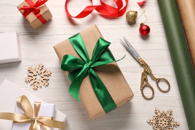 Photo of Flat lay composition with beautiful Christmas gift boxes and wrapping paper on white wooden table