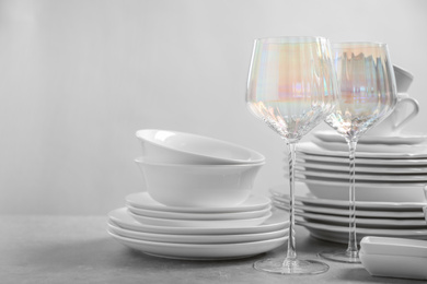 Photo of Set of clean dishes and glasses on light grey table