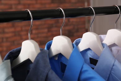 Photo of Wardrobe rack with stylish clothes near brick wall, closeup
