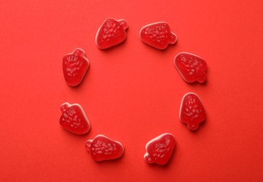 Photo of Delicious gummy strawberry candies on red background, flat lay. Space for text