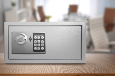 Image of Closed steel safe with electronic lock on wooden table indoors