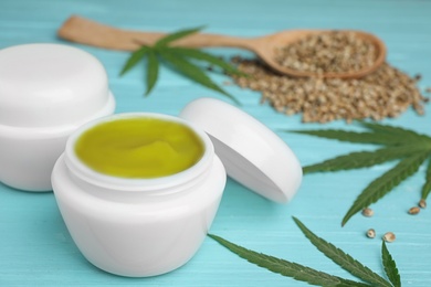 Photo of Jars of hemp cream on blue wooden table, space for text. Organic cosmetics