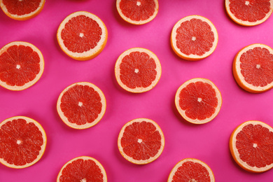 Photo of Flat lay composition with tasty ripe grapefruit slices on magenta background