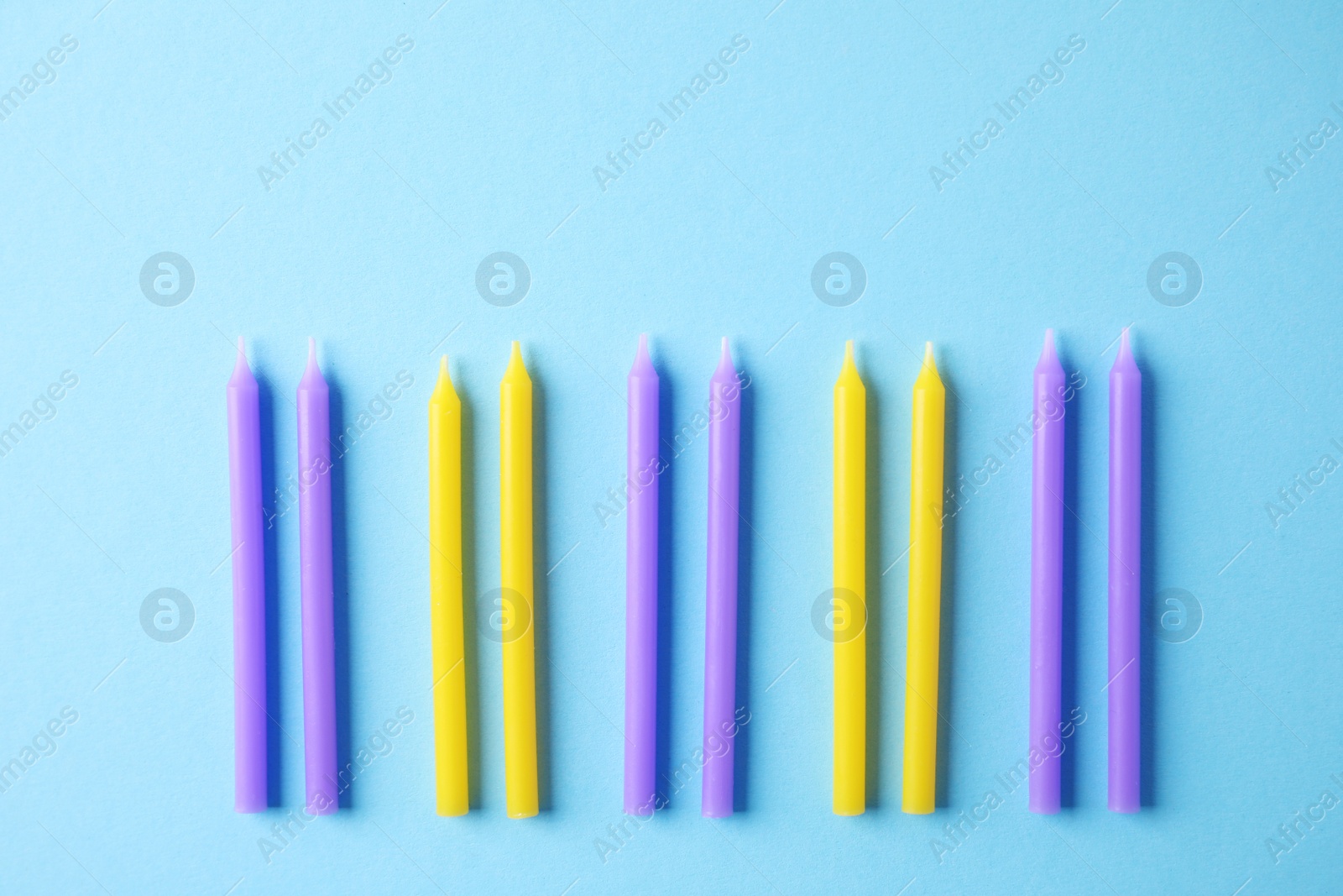 Photo of Colorful birthday candles on light blue background, flat lay