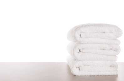 Photo of Fresh towels on light grey table against white background. Space for text