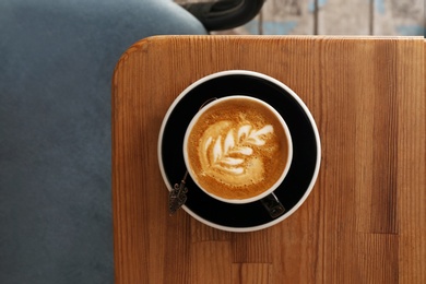 Photo of Cup of fresh aromatic coffee on wooden table, top view