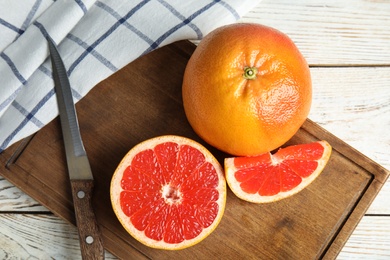 Photo of Flat lay composition with grapefruits, board and knife on wooden background