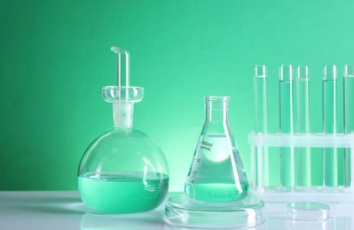 Photo of Laboratory analysis. Different glassware on table against green background