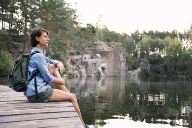 Young woman on wooden pier near lake. Camping season