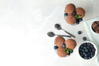 Photo of Glass bowls of chocolate ice cream and blueberries served on light table, flat lay. Space for text