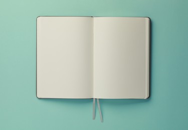 Photo of Blank notebook on turquoise background, top view