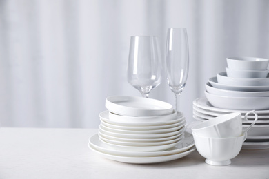 Photo of Set of clean dishware on white table