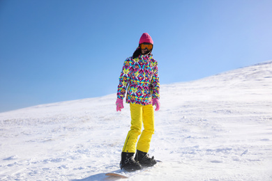 Photo of Young woman snowboarding on hill. Winter vacation