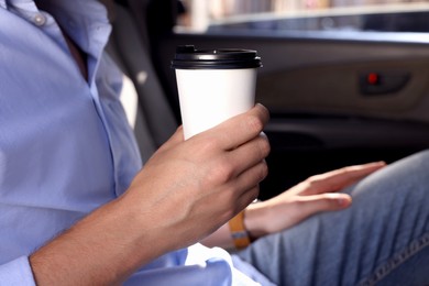 Photo of Coffee to go. Man with paper cup of drink in car, closeup