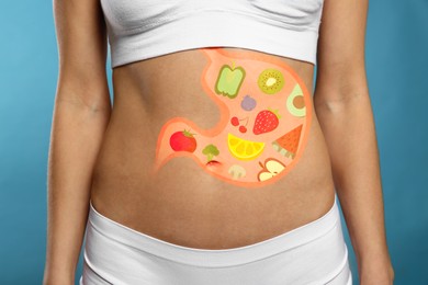 Image of Woman with image of stomach full of food drawn on her belly against light blue background, closeup. Healthy eating habits