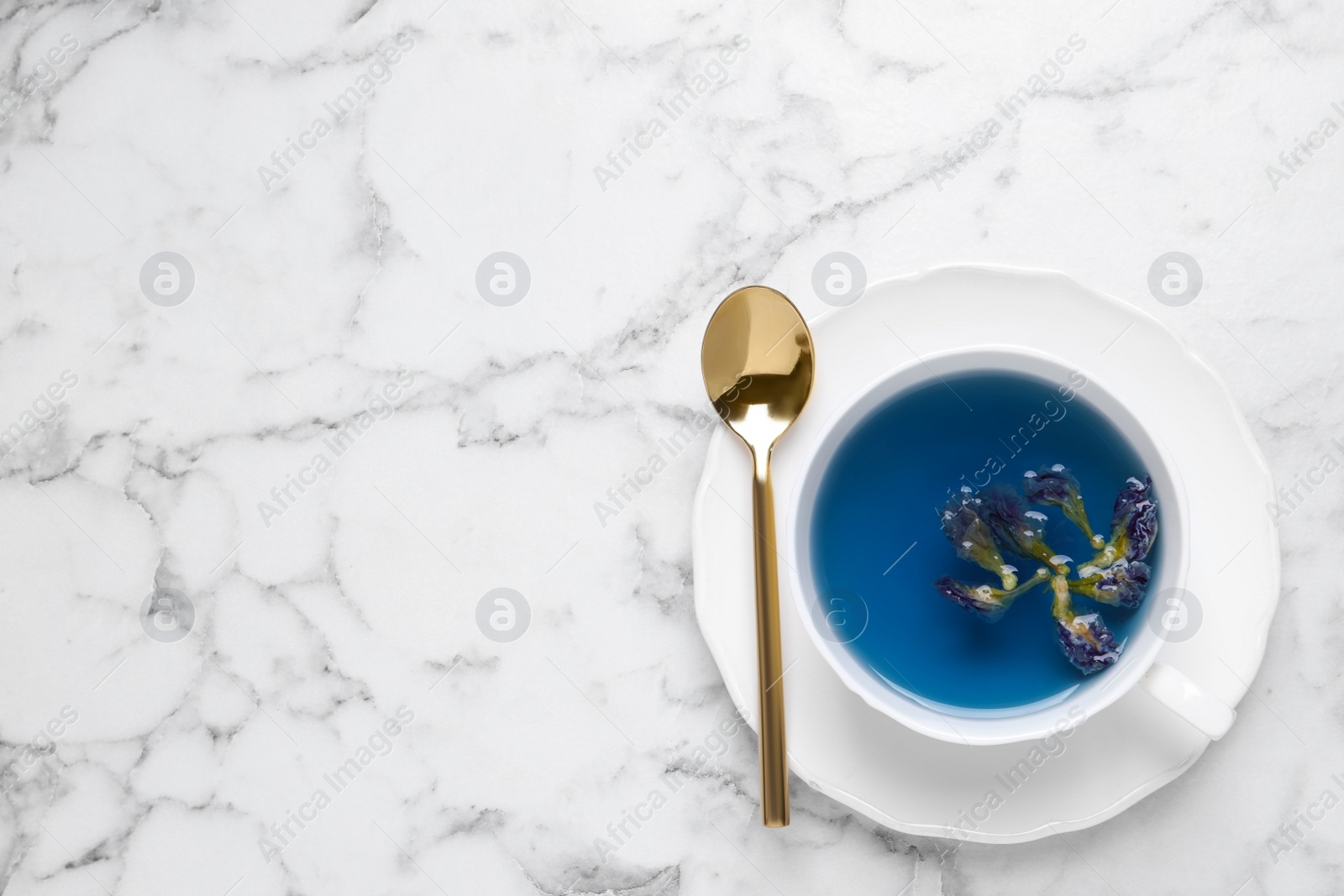 Photo of Organic blue Anchan in cup on white marble table, top view with space for text. Herbal tea